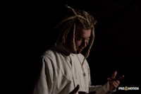 a man with dreadlocks in front of a black background